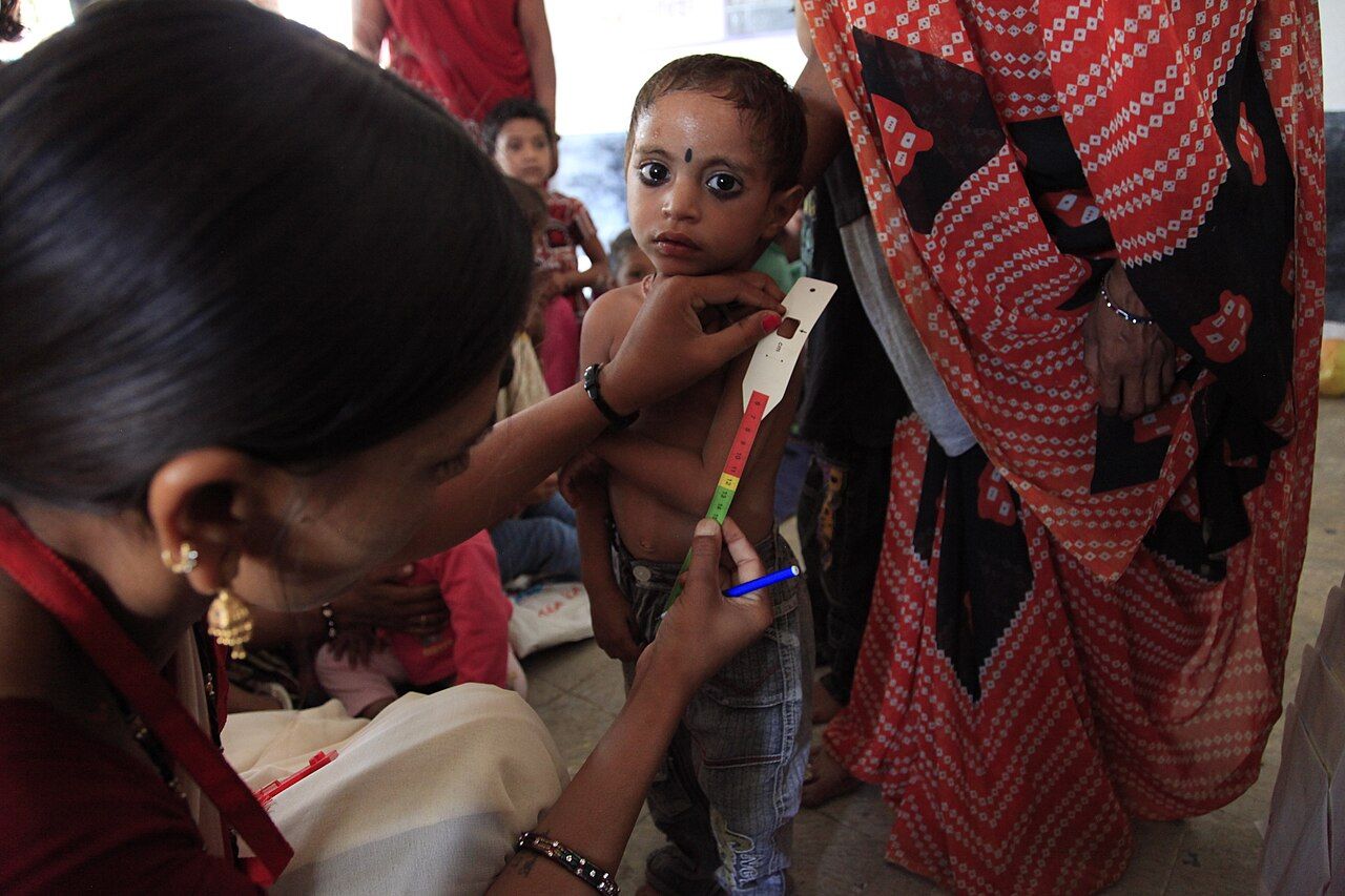 A health worker measuring mid-upper-arm circumference to screen for malnutrition